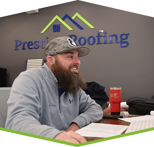 Side profile of a bearded Prestige Roofing specialist working at an office desk