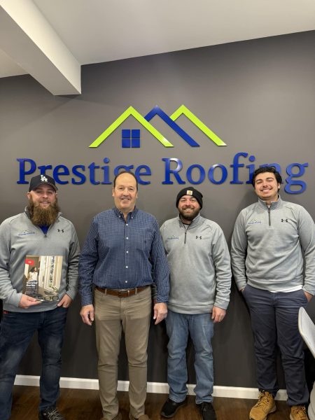 Four smiling male team members from Prestige Roofing posing together