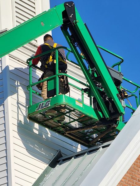 Storm damage roof repair specialist working from a high-reach lift