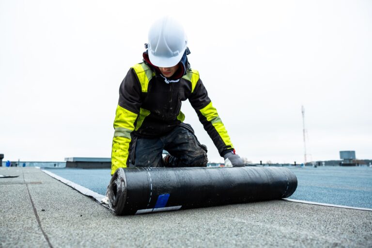 Worker installing waterproof membrane on a flat roof
